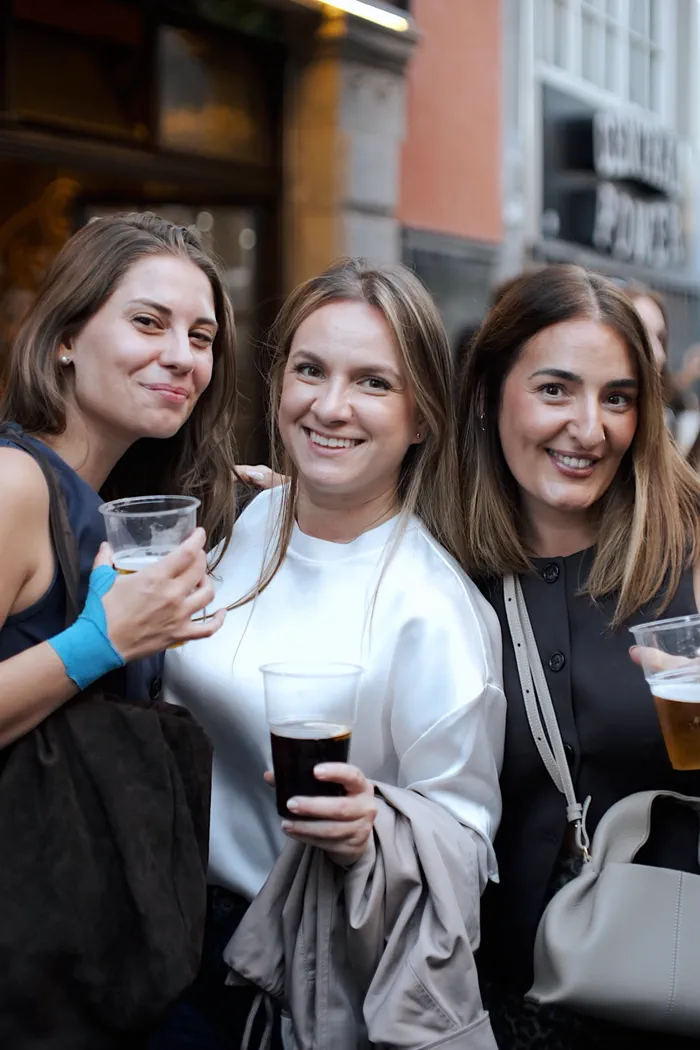 Tres socias de la comunidad sonriendo con sus bebidas en la calle