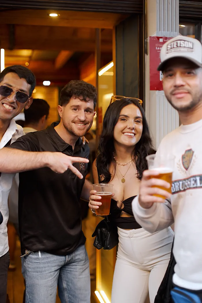 Cuatro miembros de la comunidad posando con una caña en la puerta de un bar de Zúrich