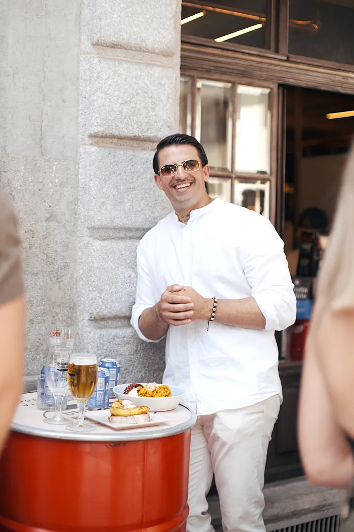 Miembro de la comunidad apoyado en la fachada, sonriendo